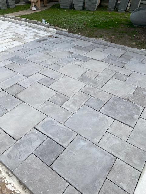 A SanStone patio paved in grey stone in a mixed-size pattern